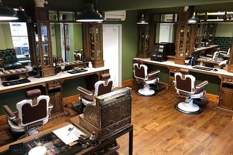 Inside Luke's: green walls, oak cabinets, leather barber chairs and an old brass till.